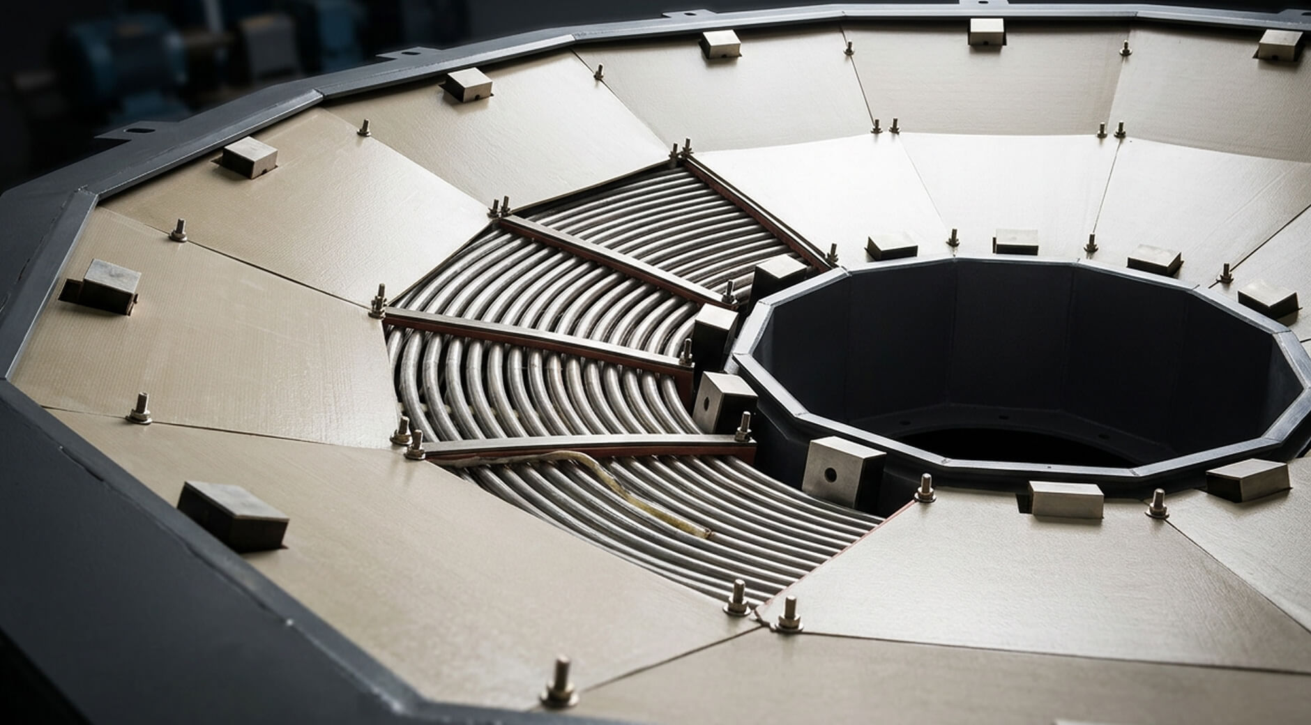 Interior view of a large industrial pressure vessel or heat exchanger end cap with curved tube bundle and bolted flange ring.
